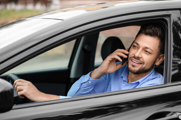 Handsome businessman talking by mobile phone in modern car