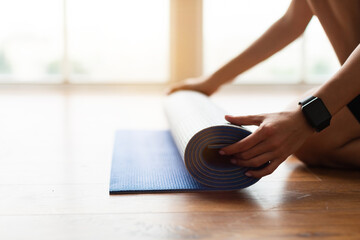 Fototapeta premium Closeup of young woman unrolling yoga mat on floor