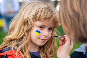 Ukrainian flag on kids cheek. No war with Ukraine. Putin attack Ukrainian people.