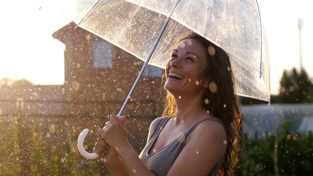 Happy young woman dancing and having fun with umbrella outdoor at sunny weather