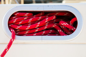 Rope compartment on a sailing yacht with red ropes inside.