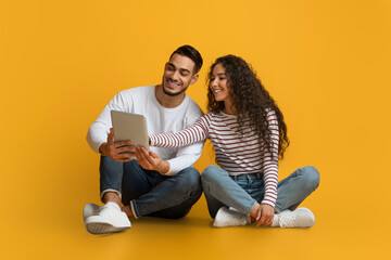 Portrait Of Happy Middle Eastern Couple With Digital Tablet Relaxing On Floor