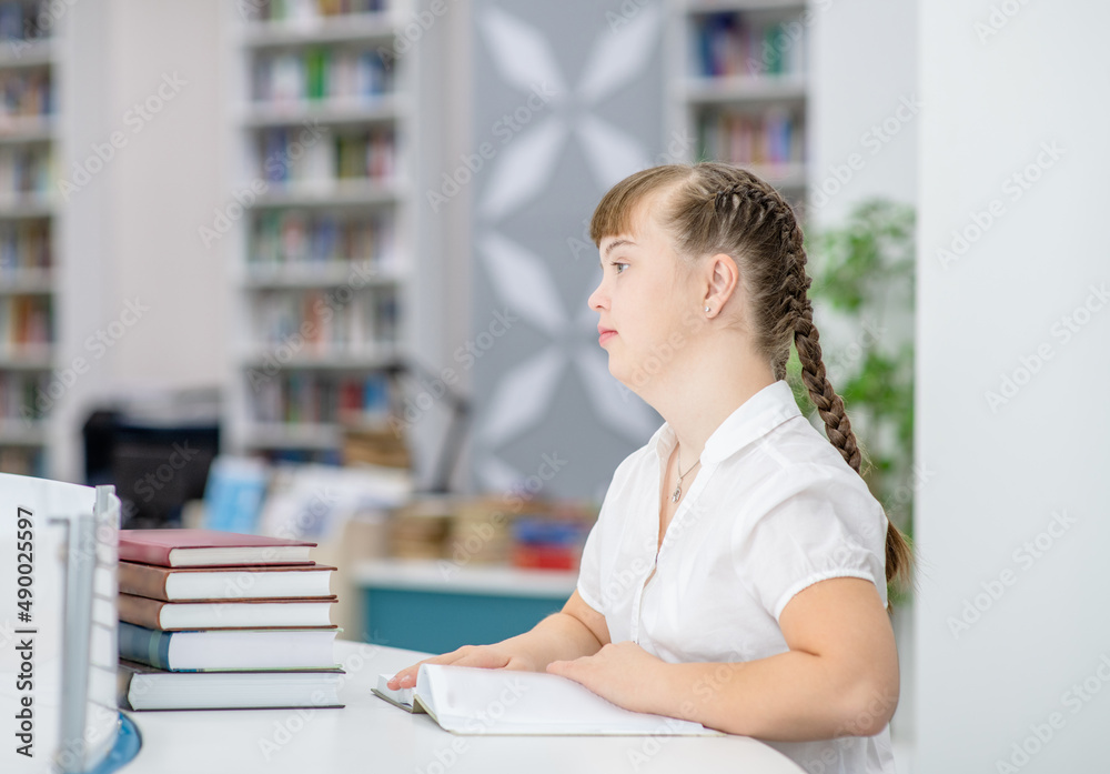 Wall mural young girl with syndrome down at library. empty space for text