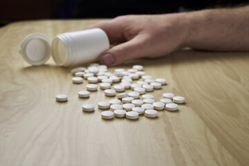 a man pours pills out of a plastic bottle on the table