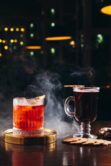 Smoked old fashioned cocktail and mulled wine on the table on dark background