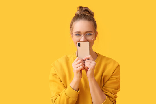 Pretty Young Woman With Mobile Phone On Yellow Background