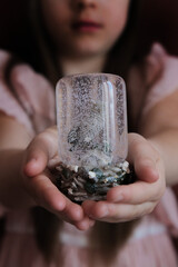 Little girl holding a glass bowl with an owl house and artificial snow on the background