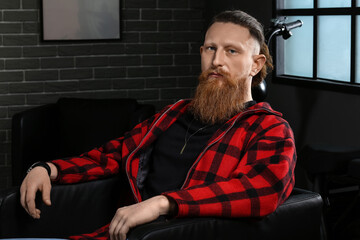 Obraz na płótnie Canvas Portrait of handsome bearded man sitting in armchair at home