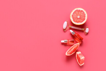 Composition with bottles of essential oil, facial massage tool and grapefruit pieces on color background