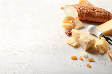 Pieces of tasty Parmesan cheese and bread on light background