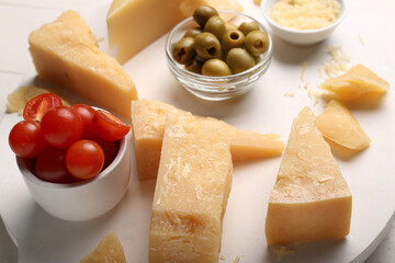 Board with pieces of tasty Parmesan cheese on table