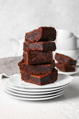 Plates with pieces of delicious chocolate brownie on light background