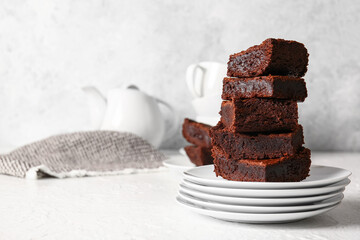 Plates with pieces of delicious chocolate brownie on light background