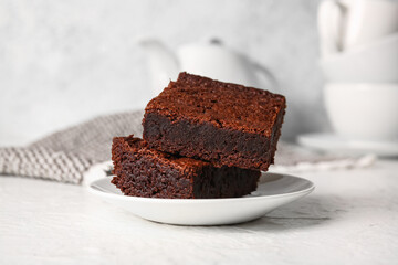 Plate with pieces of delicious chocolate brownie on light background
