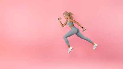 Young Woman Running With Dumbbells Isolated On Studio Background