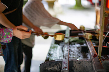 神社に参拝する人たちが手水の柄杓で身を清める