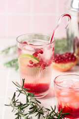 Glasses of tasty pomegranate cocktail on tile background