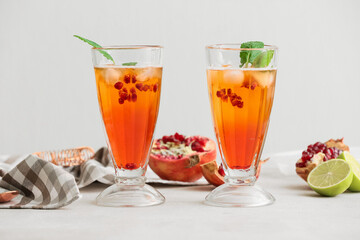 Glasses of tasty pomegranate cocktail on white background