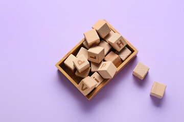 Box with wooden cubes on color background