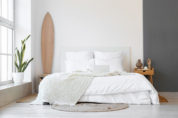 Interior of modern bedroom with wooden surfboard and table