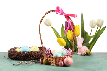 Fototapeta na wymiar Basket and nest with painted Easter eggs and tulip flowers on table against white background