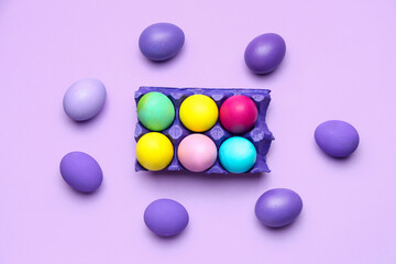 Holder with painted Easter eggs on color background