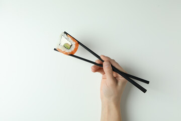 Female hand hold chopsticks with roll on white background