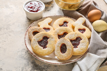 Plate with tasty Easter cookies on beige background