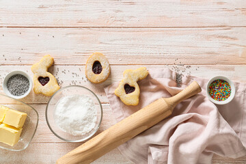 Tasty Easter cookies and ingredients on white wooden background