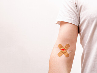 Patch with red heart on arm after donating blood