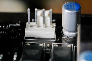 Extreme close-up shot of a four-pin (4-pin) connector on a dusty computer motherboard and a...
