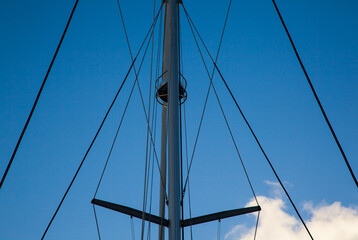 Fototapeta premium Mast of a sailing yacht against a blue sky with clouds.