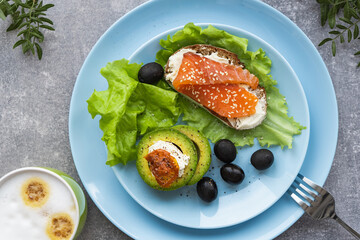 Healthy breakfast. Sandwich with smoked salmon, avocado cheese on lettuce salad leaves and coffee