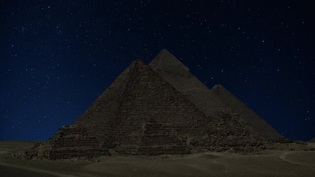 The Giza Great Pyramid complex in Egypt near Cairo under night sky with stars, timelapse 4k