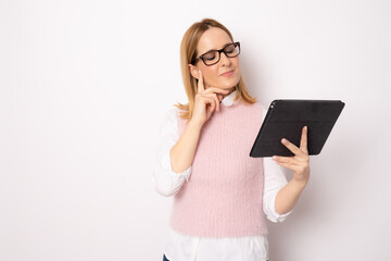 Naklejka premium Young pensive business woman holding tablet standing isolated over white background. Business concept.