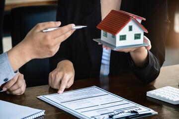 Loan signing concept, refinancing, home and land purchase, rental accommodation, female real estate agent or bank employee pointing to a contract or agreement with a male client to  to Buy a dwelling.