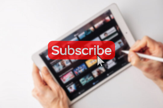 Subscription plan. Red online video subscribe button. Internet service on laptop digital tablet blured technology background. Visual contents concept. Social networking service.