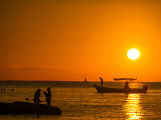 beautifal sunset at the shoreline, with boats, birds and persons at mexico
