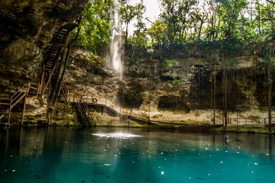 Cenote Ek Balam X'Canche near Valladolid, Yucatan, Mexico. Blue water with little waterfall
