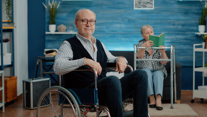 Portrait of senior man with disability living in nursing home. Elder disabled person in wheelchair and looking at camera, needing support and assistance from caregiver as facility resident.