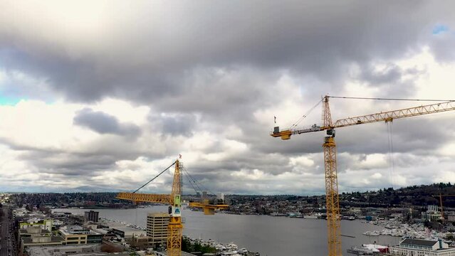 Bird's perspective of construction cranes on a cloudy but bright day.