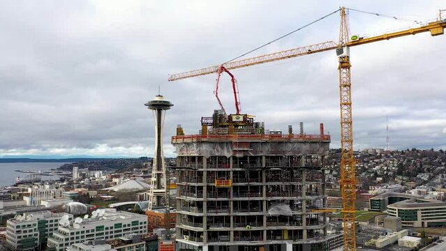 Aerial of a crane construction site creating a skyscraper with the Seattle Space Needle in the background.