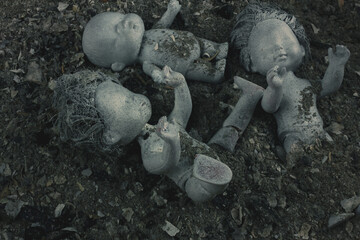 Abandoned dolls in a pile of grey ashes. Violence against the Ukrainian people concept. War,...