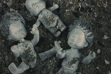 Abandoned dolls in a pile of grey ashes. Violence against the Ukrainian people concept. War,...