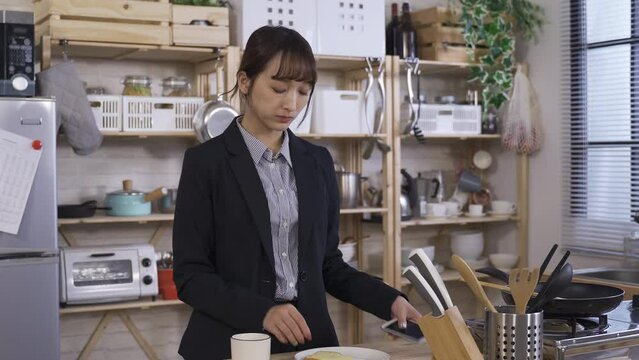 waist up businesswoman is answering and talking on the phone with hand gestures while eating breakfast at a bright home kitchen.