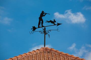 Weather vane on blue sky