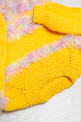 Warm children's yellow sweater on a white background, top view. Details