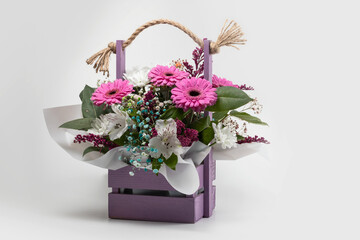 Beautiful bouquet of bright flowers in wooden basket on white background