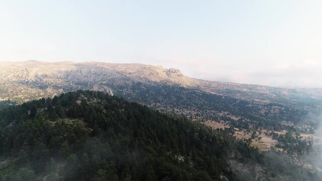 Aerial backward view of a valley and its surrounding mountains with mist. District of Akkar. Lebanon. Real time