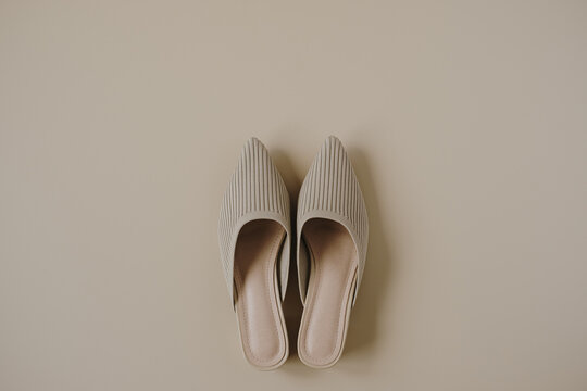 Flat lay of trendy female shoes on neutral pastel beige background. Aesthetic luxury fashion accessory. Top view